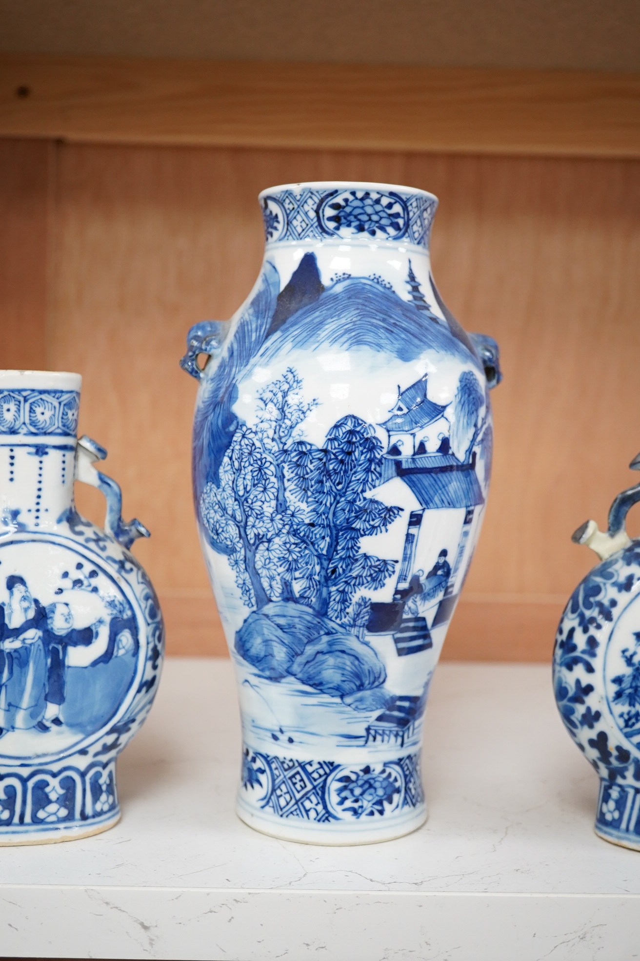 Late 19th century Chinese vases; pair of small Chinese blue and white moon flasks and a larger Chinese blue and white landscape vase, larger vase 22cm high. Condition - one moon flask handle restored, other items fair